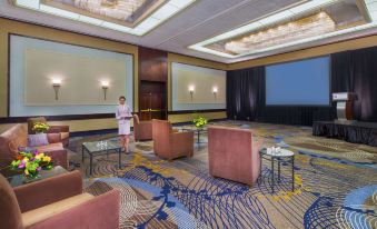 a woman in a pink robe standing in a room with chairs and a large screen at Hyatt Regency Buffalo Hotel and Conference Center