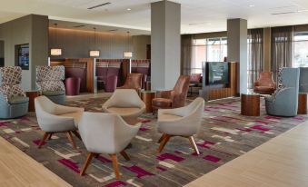 a modern hotel lobby with various seating arrangements , including chairs and couches , and a television at Courtyard Rome Riverwalk