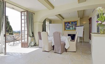 a spacious room with white chairs and a dining table set up for a meeting or event at Chateau le Cagnard