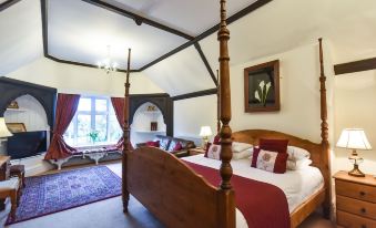 a cozy bedroom with a four - poster bed , red curtains , and a painting on the wall at The Bentley Brook Inn