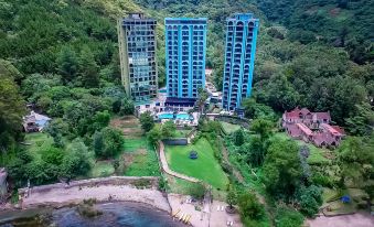 aerial view of a residential area with three blue apartment buildings surrounded by trees and grass at Hotel la Riviera de Atitlán
