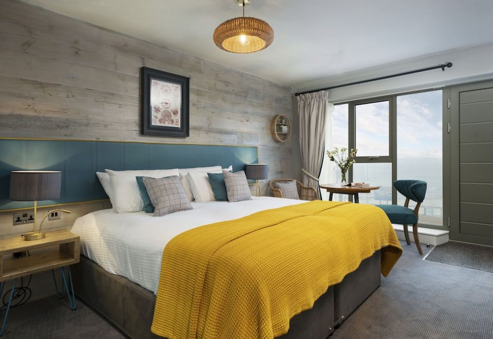 a large bed with a yellow blanket is in a room with wooden walls and a window at The Old Success Inn