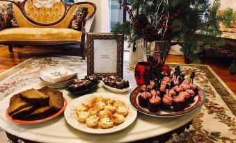 a table is set with various food items , including pastries and chocolate - covered treats , in a living room at Dragonfly Bed and Breakfast