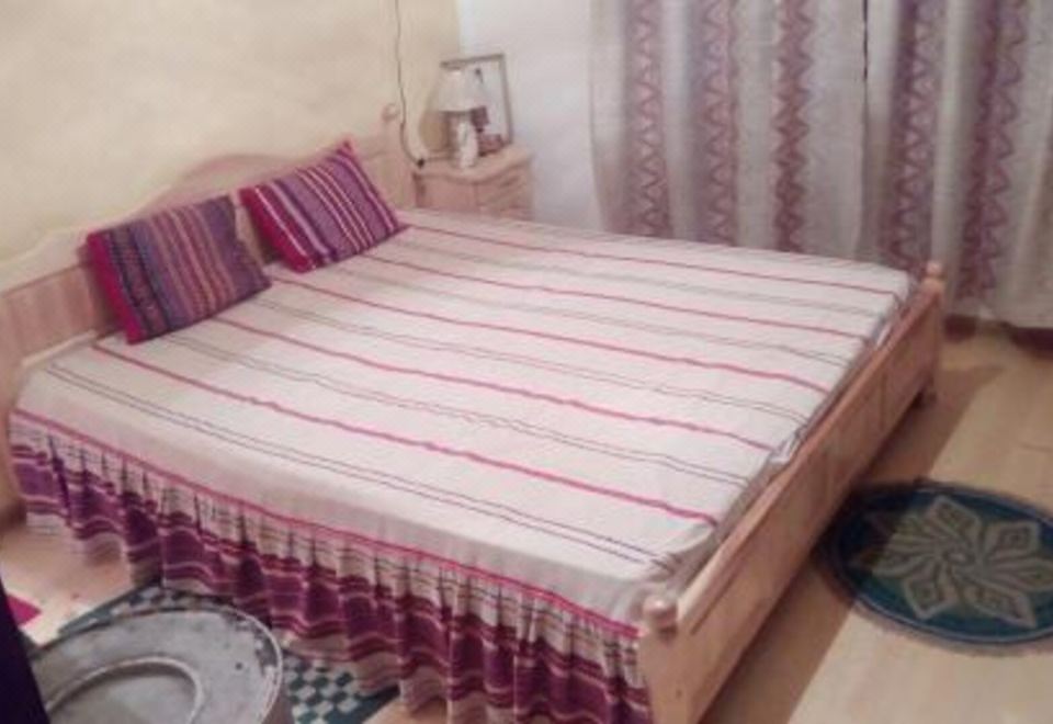a bed with a striped comforter and pillows , along with a chair in the background at Villa Elena