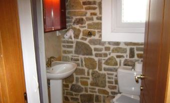"a bathroom with a stone wall , white toilet , and sink , along with the name "" cdga "" on the door" at Victoria Limnos
