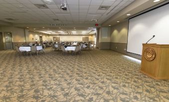 a large conference room with several tables and chairs , a projector screen , and a television at Carter Caves State Resort Park