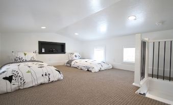 a modern bedroom with two beds , white bedding , and a tv on the wall , as well as a carpeted floor at The Escape to East Zion
