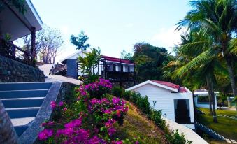 a beautiful house with a red roof , surrounded by lush greenery and purple flowers , located on a hillside at Marina Del Ray