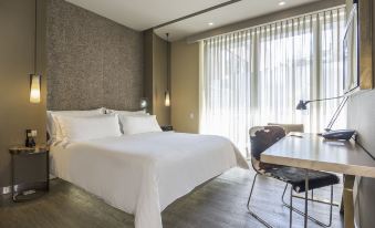 a modern bedroom with a large bed , white sheets , and a view of the city at Bog Hotel