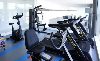 a well - equipped gym with various exercise equipment , including treadmills and weight machines , on a blue and gray floor at Tulip Inn Itaguai