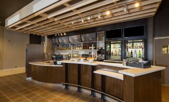 a modern restaurant with a bar counter and dining area , featuring wooden floors and cabinets at Courtyard Bay City