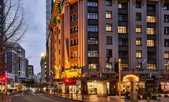 a city street at night , with a tall building on the left side of the street at DoubleTree by Hilton Wellington