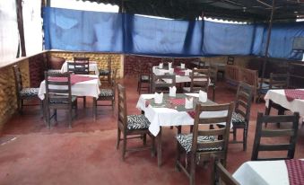 a dining area with wooden tables and chairs , white tablecloths , and blue curtains on the ceiling at Spice Garden