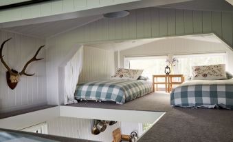 a cozy bedroom with two beds , one on top of the other , and a bathroom in the background at Extraordinary Huts Ltd