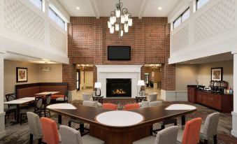 a modern , spacious lobby with a dining area and a fireplace , featuring brick walls and wooden furniture at Homewood Suites by Hilton Newtown - Langhorne