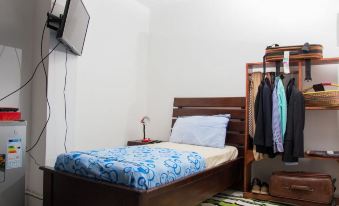 a small bedroom with a single bed , a closet , and a television mounted on the wall at EastWest Hospitality
