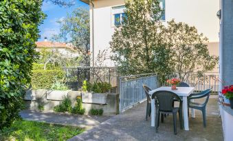 a patio with a table and chairs is set up next to a house , surrounded by greenery at Mansarda