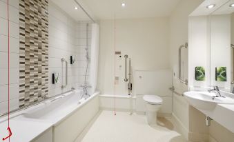 a bathroom with a white bathtub , toilet , and shower , as well as a toilet seat lift at Huddersfield North