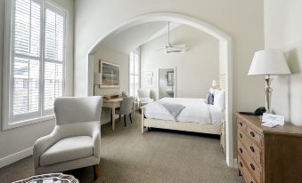 a white bedroom with a bed , dresser , and chair , along with a living area containing a couch and coffee table at Briar Barn Inn