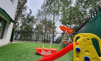 a colorful playground with various toys , including a slide , swings , and a boat , set against the backdrop of trees and a lake at Hotel Bliss