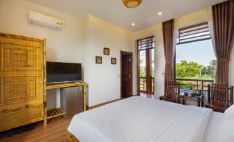 a bedroom with a large bed , television , and sliding glass doors leading to an outdoor balcony at MH Cherish Homestay