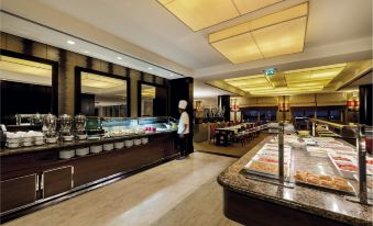 a large dining area with a long buffet table filled with various food items , including fruits , vegetables , and desserts at Hotel Baia