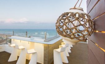 a rooftop bar with white chairs and tables , overlooking the ocean , creating a relaxing atmosphere at Hotel Meridional