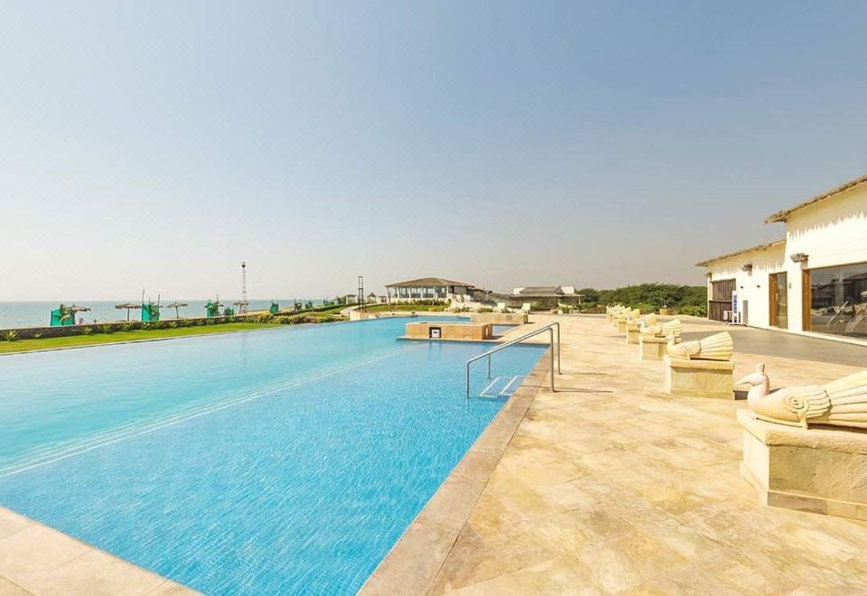 a large outdoor swimming pool surrounded by grass and trees , with several lounge chairs placed around the pool area at Serena Beach Resort