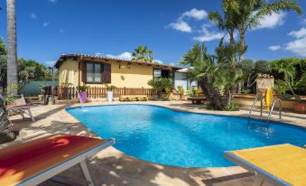 a beautiful villa with a swimming pool , umbrellas , and sun loungers , surrounded by lush greenery and clear blue skies at Albert