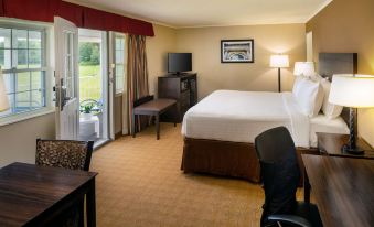 a hotel room with a king - sized bed , a television , a dining table , and a window at Best Western University Inn