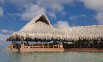 a wooden boat docked in a body of water , with a thatched roof structure in the background at Hotel Las Islas