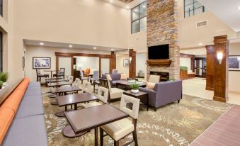 a spacious , well - lit lobby with multiple couches and chairs , as well as a fireplace in the center at Staybridge Suites Benton Harbor - ST. Joseph