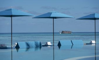 a large body of water with several umbrellas and chairs set up on the beach at Four Seasons Resort Maldives at Kuda Huraa