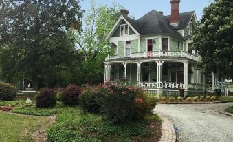 a large green house surrounded by trees and bushes , with a driveway leading up to it at Peacock Place