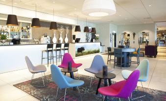 a modern lounge area with colorful chairs and tables , a bar , and a variety of seating options at Thon Partner Elgstua Hotel