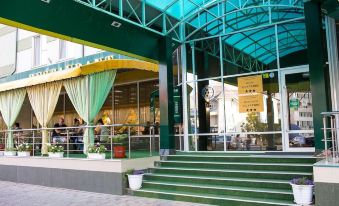 a green storefront with a large yellow awning and stairs leading up to it , where people are sitting at tables at Vila Verde