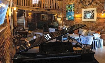 a grand piano is placed in the middle of a room with wooden walls and ceiling , surrounded by furniture at Tewinbury