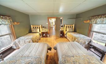 a room with three beds , each made up with white sheets and floral bedspreads , arranged in a row at RoosterComb Inn