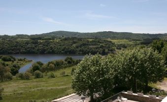 a scenic view of a lake surrounded by green hills with trees and bushes on the hills at Pousada de Portomarin