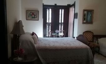 a bedroom with a bed , chair , and table in front of a window with blinds at Smithville Historical Museum and Inn