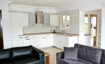 a modern kitchen and living room with white cabinets , a black couch , and a gray couch at The Lansdown