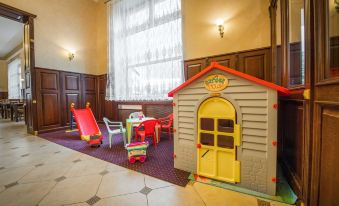 a room with a playhouse and a table filled with chairs , all under the shade of curtains at Hotel Europa