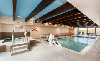 a large indoor swimming pool with a blue ceiling , surrounded by white walls and a building with stairs leading up to it at Home2 Suites by Hilton Omaha/West