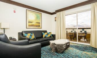a living room with a black leather couch , coffee table , and large window overlooking the mountains at Ute Mountain Casino Hotel