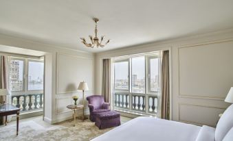 a luxurious bedroom with white walls , large windows , and a balcony offering views of the city at Four Seasons Hotel Cairo at the First Residence