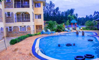 a large swimming pool with a blue and white striped umbrella on the right side at Calabash Hotel