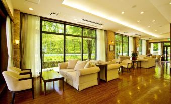 a large , well - lit living room with multiple couches and chairs arranged around a dining table at Hotel Hakuba