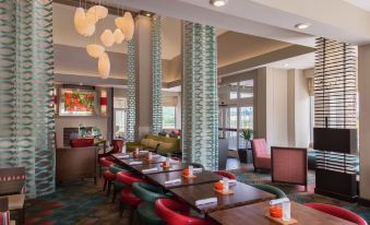 a dining room with multiple tables and chairs , as well as a living area with couches at Hilton Garden Inn Bristol