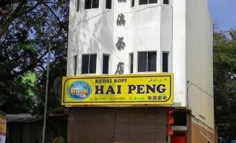 "a white building with a yellow sign that says "" kedai kopi hat peng "" on the front" at De' Chukai Hotel