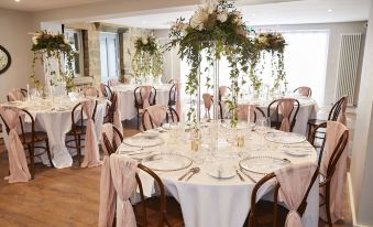 a beautifully decorated dining room with round tables covered in white tablecloths and adorned with flowers at The Lawrence